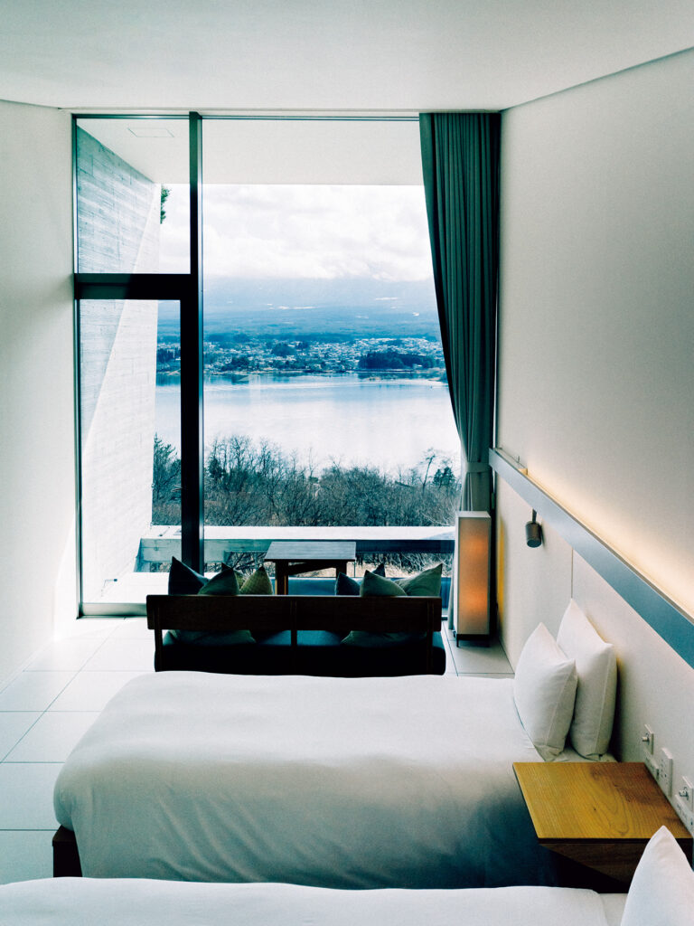 客室は白を基調としたミニマルなインテリア。窓の向こうに広がる河口湖の美しい景色を引き立てる。