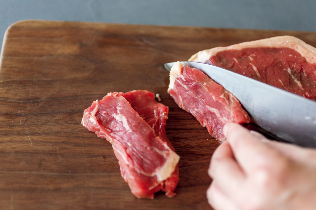 ステーキ肉を斜めそぎ切りにする。断面が広く取れて、口当たりもやわらかに。