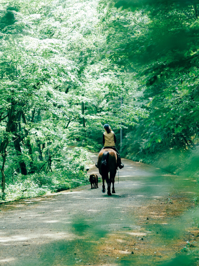 雑木林の中に建てた家で動物たちと暮らす古賀貴子さんの日課は乗馬。隣の馬場から愛馬グレースアローンにまたがり家の前の道に出、近くをぐるりと周遊して戻ってくる。