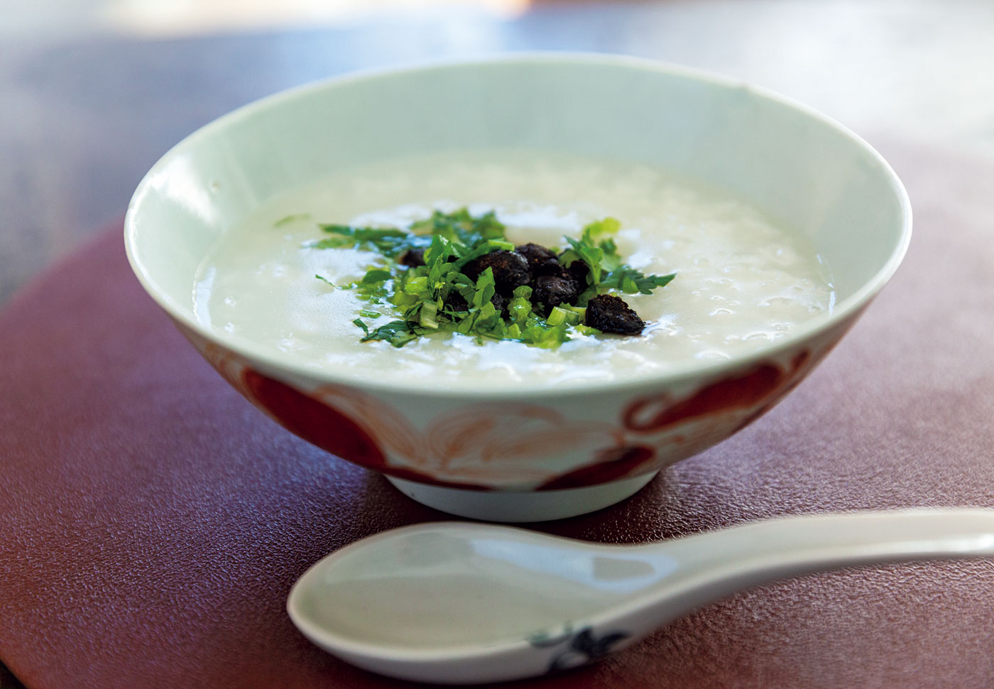 「一休寺納豆」をのせたおかゆ。ゴマ油で和えたシャンツァイなどの香味野菜と一緒に食べる。おかゆ以外にもスープに入れたり、炒め物の味付けに使ったりなど、調味料や出汁の代わりとしても使える。使い方はほぼ味噌と一緒。,ウー・ウェン,料理研究家 |  「一休寺納豆」をのせたおかゆ。ゴマ油で和えたシャンツァイなどの香味野菜と一緒に食べる。おかゆ以外にもスープに入れたり、炒め物の味付けに使ったりなど、調味料や出汁の代わりとしても使える。使い方はほぼ味噌と一緒。
