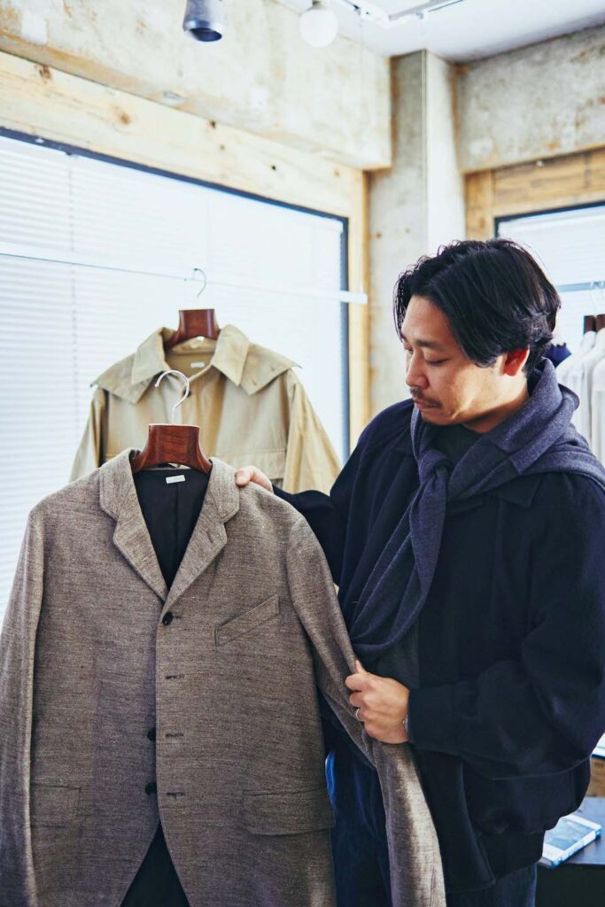 1910年代のサックジャケットを手に持つ重松さん。作りの確かな古着がインスピレーションソースに。
