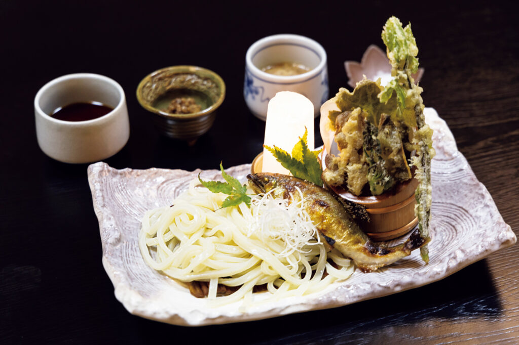 美濃鮎にんめん￥1,980。にんめんは、昭和30年代まで食べられていた鮎出汁のうどんのこと。鮎1匹を使った鮎味噌を、醤油と胡麻の2種のつけ汁に混ぜながら食べる。鮎の天ぷらと塩焼きも付く。