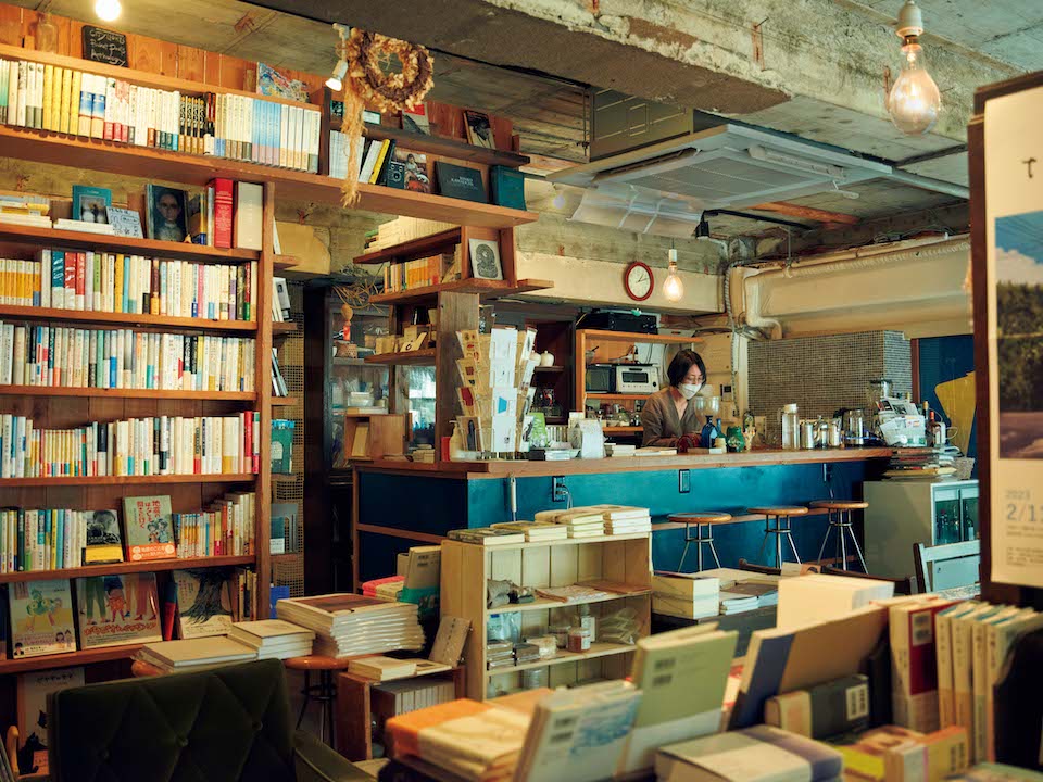 案内人の平沢さんいわく「熊本は素晴らしい書店が集まる街」。新旧の個性的な店々のなかでも、開業22年を迎える『橙書店』（熊本市中央区練兵町54‒2F）の存在が際立つ。店主の田尻久子さんは選書について「普通の本屋では埋もれてしまうものばかりかもしれません。社会的には少数派の人々についての本というか。私がいいと思ったものを置いているだけなんですけどね」。自然な態度で編まれた書棚は訪れる人の心に寄り添い、いま必要としている本を手に取らせる。『橙書店』の前身はカフェ『orange』。窓辺の喫茶スペースとカウンターで、田尻さんの淹れるコーヒーが飲める。