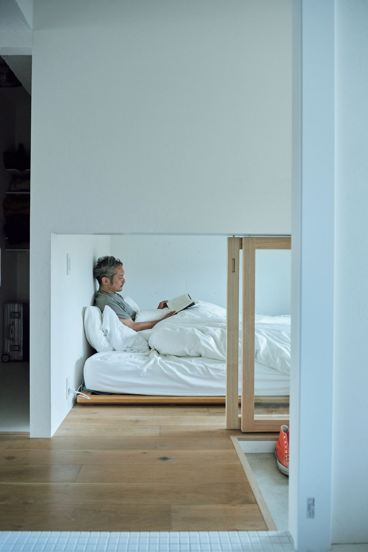 家の中の、”隠の空間”を大切にしてみる。伊藤貴亜さん、伊藤順子さんの心地よい住まい。 | 洗面スペースから寝室のほうを向いてみると、貴亜さんが休息中。手前右手の土間に並べられたスニーカーが見えるのが面白い。