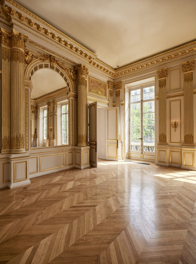 金箔が輝く木製の縁飾りがあしらわれた白壁とコリント式の列柱が見られるセレモニーホールとダイニングルーム。