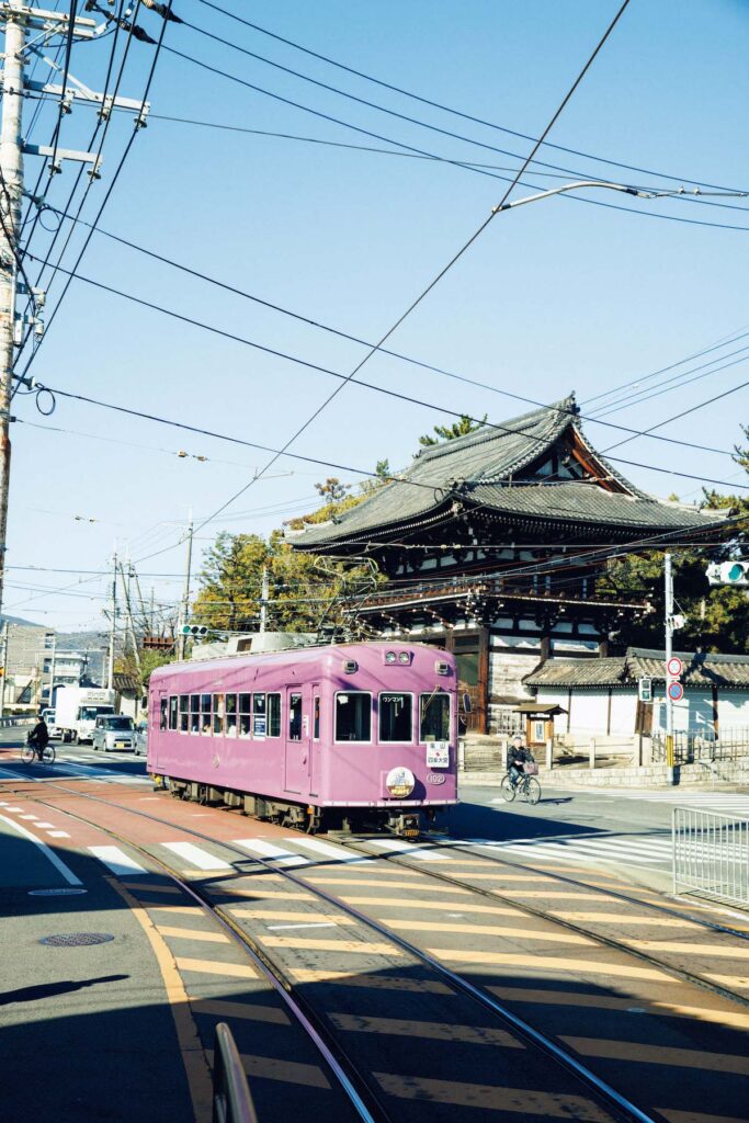 1910年に開通して以来、嵐電の名で親しまれる京福電気鉄道。京紫色と呼ばれる車両の色は100周年を機に採用されたイメージカラー。写真は広隆寺の楼門の前を走る嵐電。