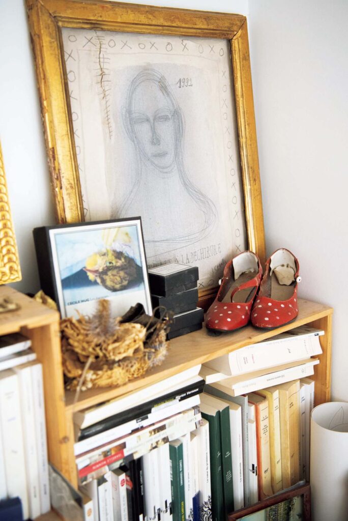 寝室のコーナー。本棚の上に、ブロカントで見つけた絵や靴のオブジェ、写真を飾る。