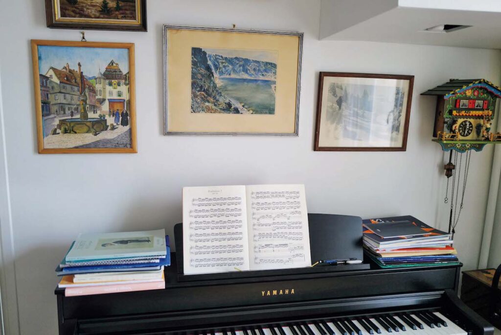 ミュージシャンであるパートナーのピアノ。こちらの壁にもブロカントで見つけた絵や写真をデコレーション。鳩時計は両親からのプレゼント。