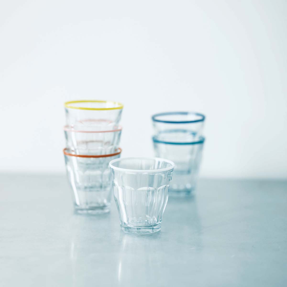 〈ザ・コンランショップ〉 デュラレックス ピカルディ 250 6 カラー リム フォー コンラン 各250㏄￥6,600 (ザ・コンランショップ ☎03‒5322‒6600) | オモムロニ。：コンランブルーをはじめ、リム部分をオリジナルカラーでアレンジした別注グラスの、6 色セット。「王道で定番ともいえるデュラレックスは、とにかく丈夫でチップもしないし、壊れることも滅多にない。だから朝に寝ぼけまなこで水を飲んでも安心です。ずっと変わらないフォルムは、いつでも買い足せて、数が増えてもスタッキングできるのが嬉しい。変わり種の色つきリムタイプだから、家族でマイグラスを決めてもいいし、来客が多いときにも便利です」。各250㏄￥6,600（ザ・コンランショップ ☎03‒5322‒6600）