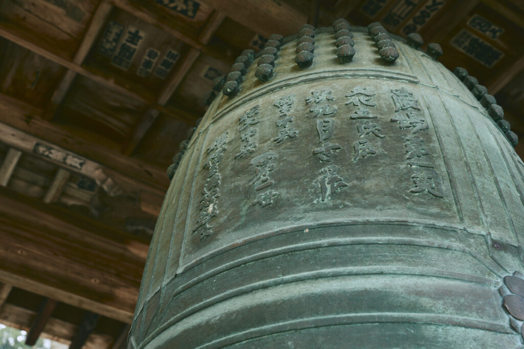 厄除鐘として参拝者が自由に撞くことができる鐘楼堂の梵鐘（ぼんしょう）。文化5（1808）年と刻まれていることから、本堂と同じ頃に再建されたものと考えられる。鐘の中央付近に7つの穴が開いているのは、戦時中の供出に向けて材質を調べた跡。ところが幸運にも難を逃れ、今も音を響かせている。
