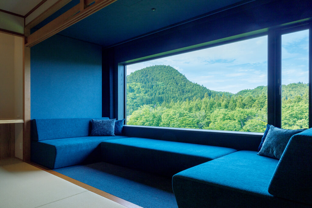山の緑が映える客室の「紺碧の間」。ソファもゆったりサイズで心地いい。