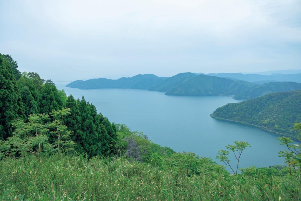 滋賀・奥琵琶湖で聖なる水辺を歩く旅。後編 | 1583年の賤ヶ岳の戦いの舞台となった賤ヶ岳の山頂には、リフトに乗れば5分ほど。琵琶湖と余呉湖、長浜の町並みが見渡せる絶景が待っている。空と湖の境が曖昧で、幽玄な風景だ。