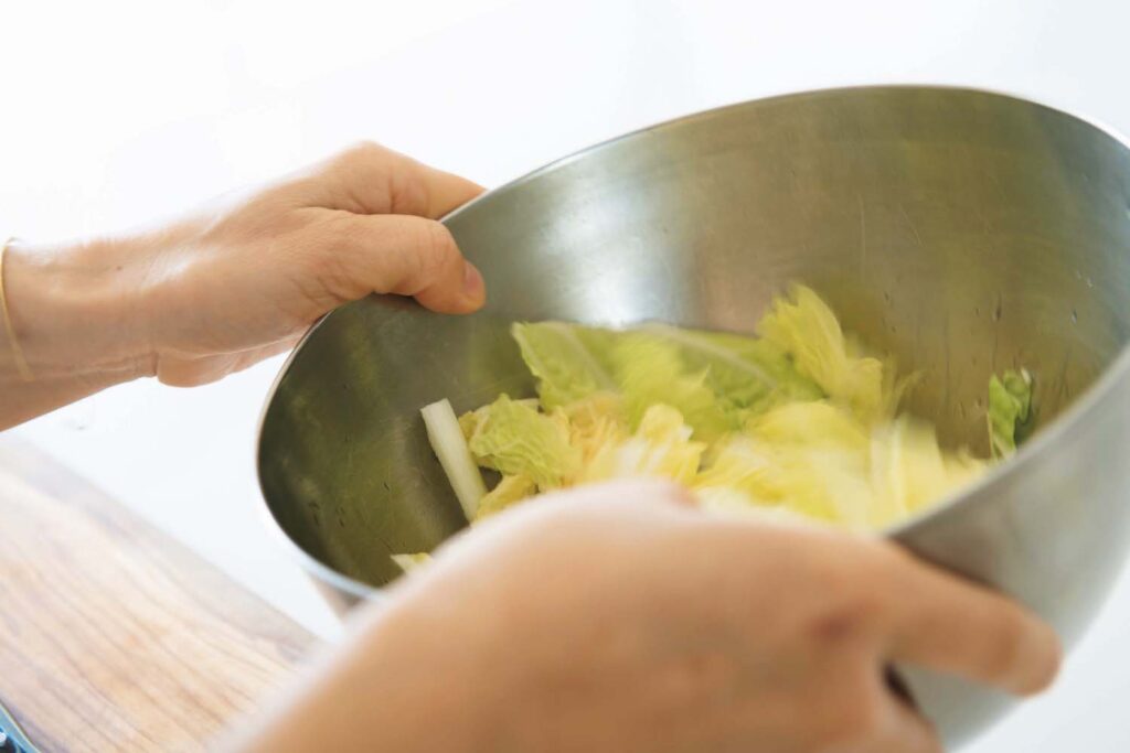 白菜は葉と芯で切り方を変える。葉はザク切り、芯は繊維に沿って食感を生かす。