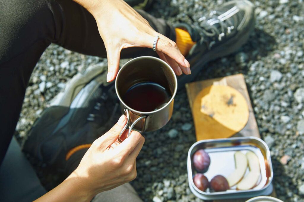 二ツ塚山頂での休憩時間、表参道『KOFFEE MAMEYA』で買ったエチオピアの中深煎りの豆で、コーヒーを淹れる佐竹さん。「保温性の高い『山専用ボトル』に熱々のお湯を入れてくれば、バーナーなしでも温かいコーヒーが飲めます」。お供はリンゴとプルーン。佐竹彩