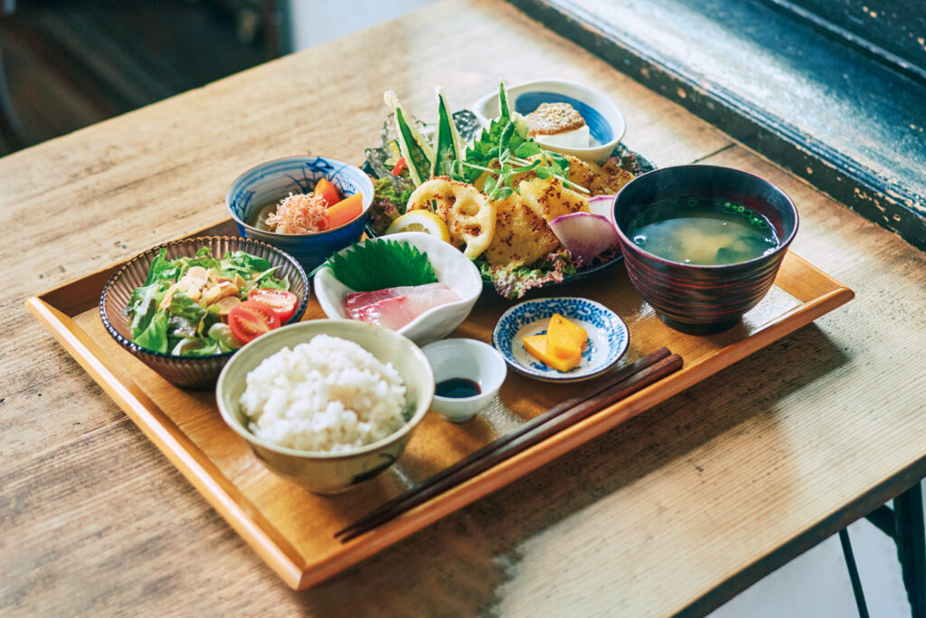 日替わりごはん￥1,500は写真の魚と野菜の天ぷらのマスタードソースがけか、鶏天のオーロラソースがけが選べる。副菜も季節の刺身や和えもの、サラダなど5品で盛りだくさん。