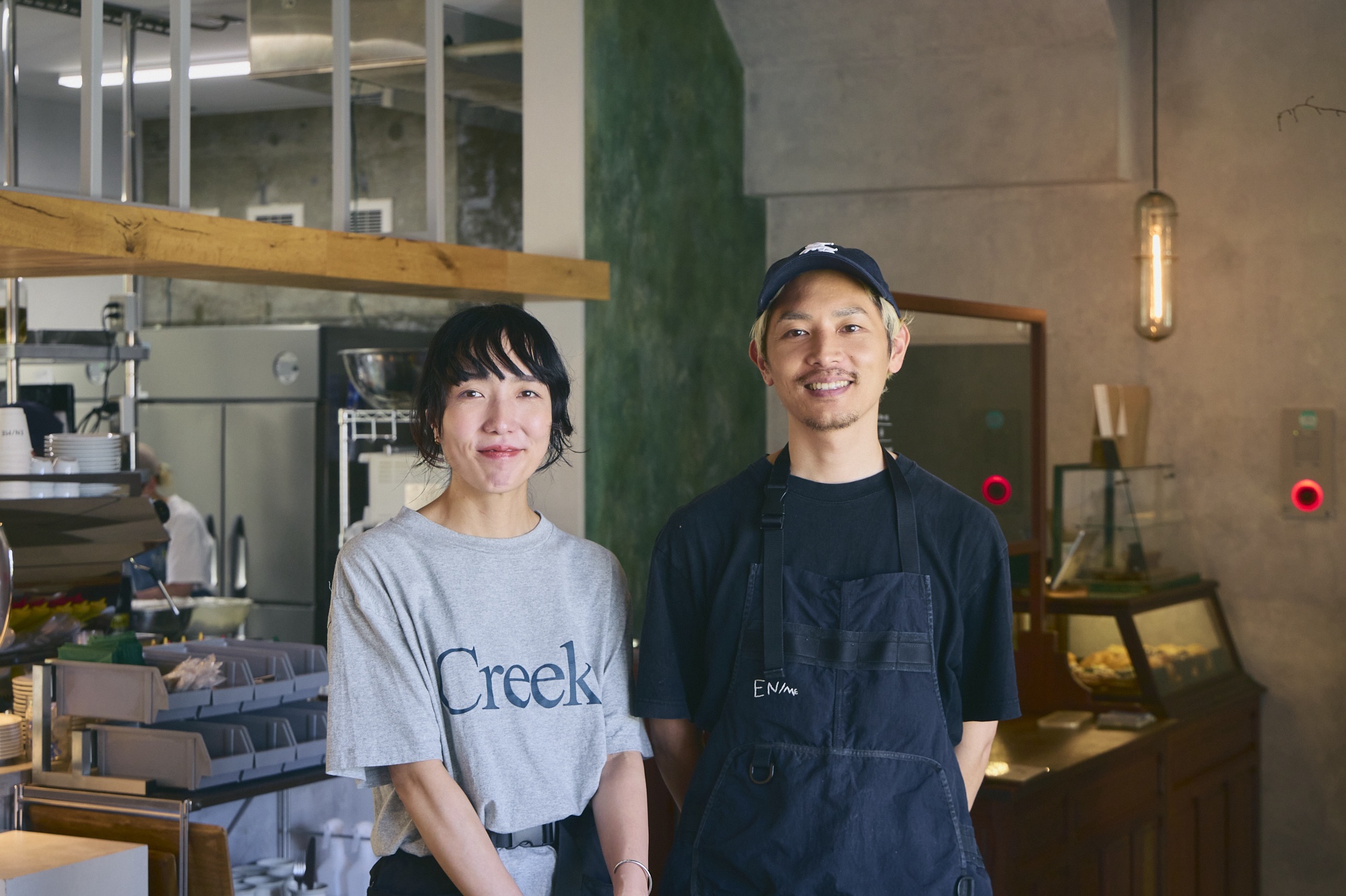 『EN/ME』のオーナー・笹原悠治さん・凛さん夫妻。悠治さんの実家がすぐ隣で精肉店を営んでいるため、ランチで登場するハンバーガーのパテのおいしさも自慢。凛さんは普段はカフェに立ちながら、フラワーデザイナーとしての顔も持つ。