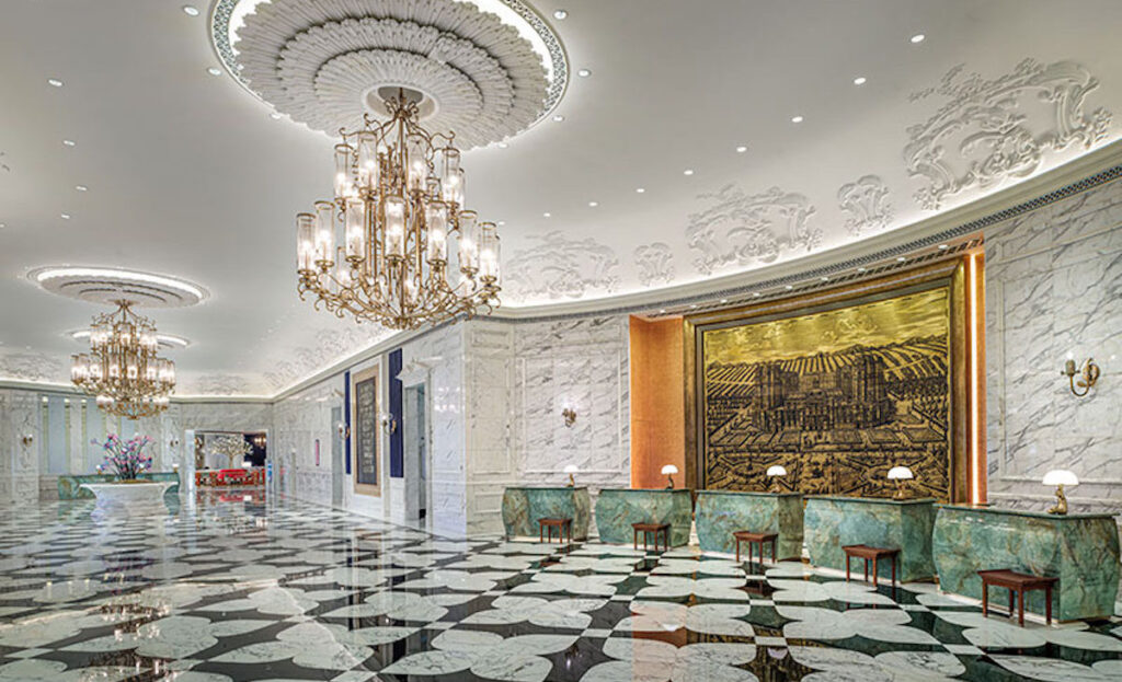 マカオで出合う、東洋と西洋の調和。リゾートホテル『Grand Lisboa Palace Resort Macau』で過ごす、贅沢なひととき。 | ウェストロビー中央の壁に掛けられているのは、フランスの大トリアノン宮殿を描いた大型の絵画作品。彫金を用いて、銀の貿易港としてのマカオの歴史を表現している。