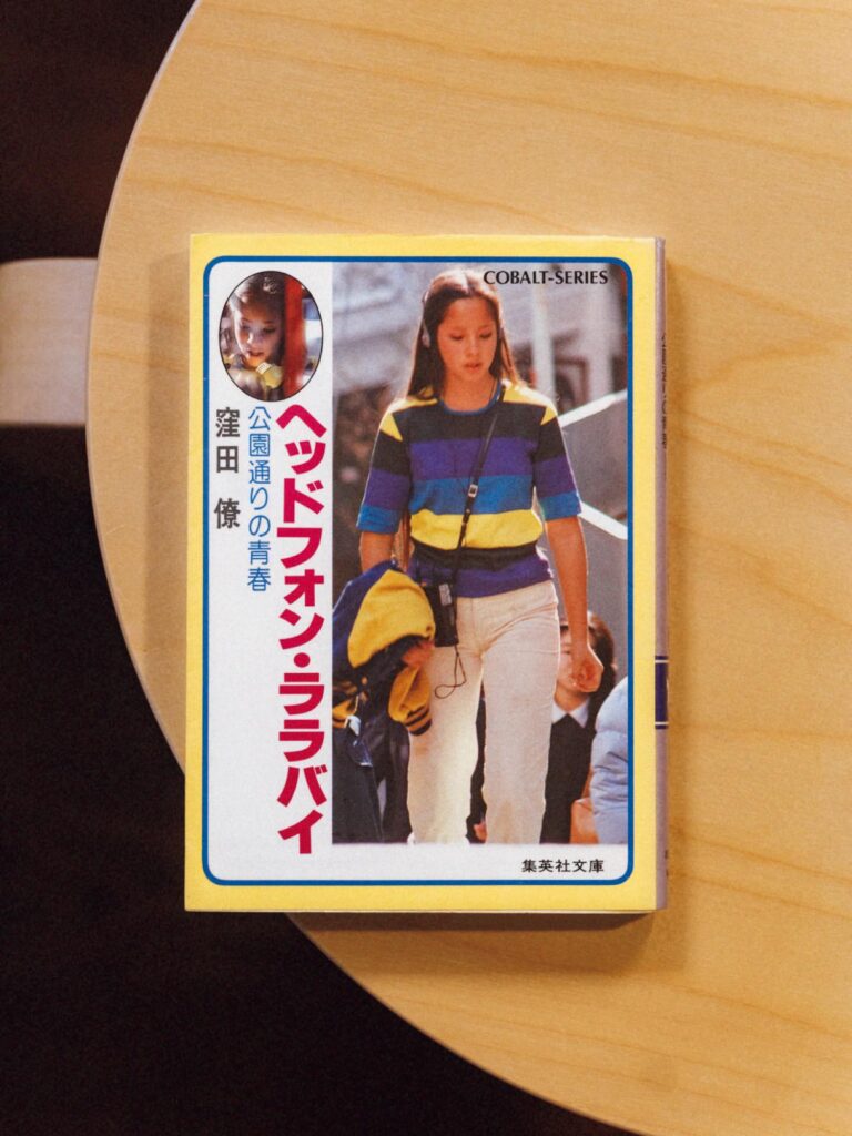歌人・穂村 弘さんが選ぶ、ずっとそばに置いておきたい本。 | 『ヘッドフォン・ララバイ 公園通りの青春』
著 窪田 僚(集英社文庫)
伝説的サブカルチャー雑誌『ビックリハウス』が主催した第1回エンピツ賞を受賞した、窪田僚の小説家としてのデビュー作。1981年発行。全4巻あり、シブがき隊の主演によって映画化された。「学園ものの話で。高校最後の夏休みに渋谷公園通りに巨大なウォールペインティングを描くというのが話のメイン。’80年代の空気が内包されていて、自分は同時代に読みました。青春の祝祭感と時代の祝祭感が両方あった頃のしるしがちりばめられている」 歌人・穂村 弘さんが選ぶ、ずっとそばに置いておきたい本。