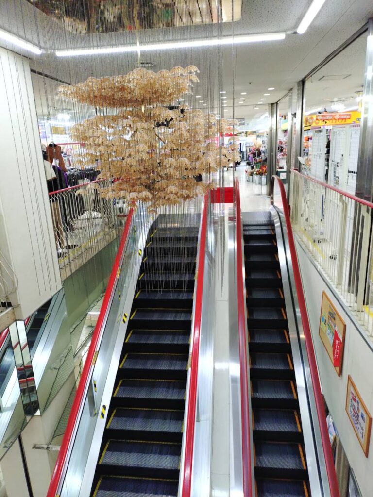 昭和の郊外型ショッピングセンターへ、タイムスリップ！ 写真と文：寺坂直毅 (放送作家) #4 岡山・新見市の『にいみショッピングタウン プラザ』内にある、エスカレーターとシャンデリア。 | 岡山・新見市の『にいみショッピングタウン プラザ』内にある、エスカレーターとシャンデリア。
