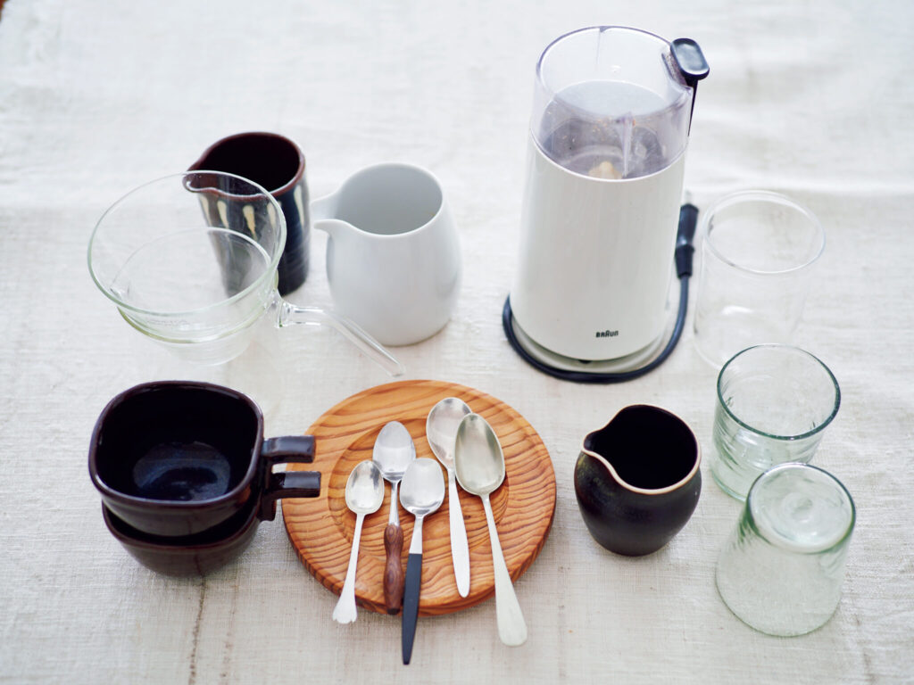 086_p048-055_料理家に教わるコーヒータイム_P10 | コーヒー道具。ミルは20年以上使っている〈ブラウン〉のもの。グラスは奥が山野アンダーソン陽子さんのもので、手前2つはフランス製。ガラスのドリッパーとポットのセットは、イギリスで購入。ミルクピッチャーも好きでいろいろ収集。