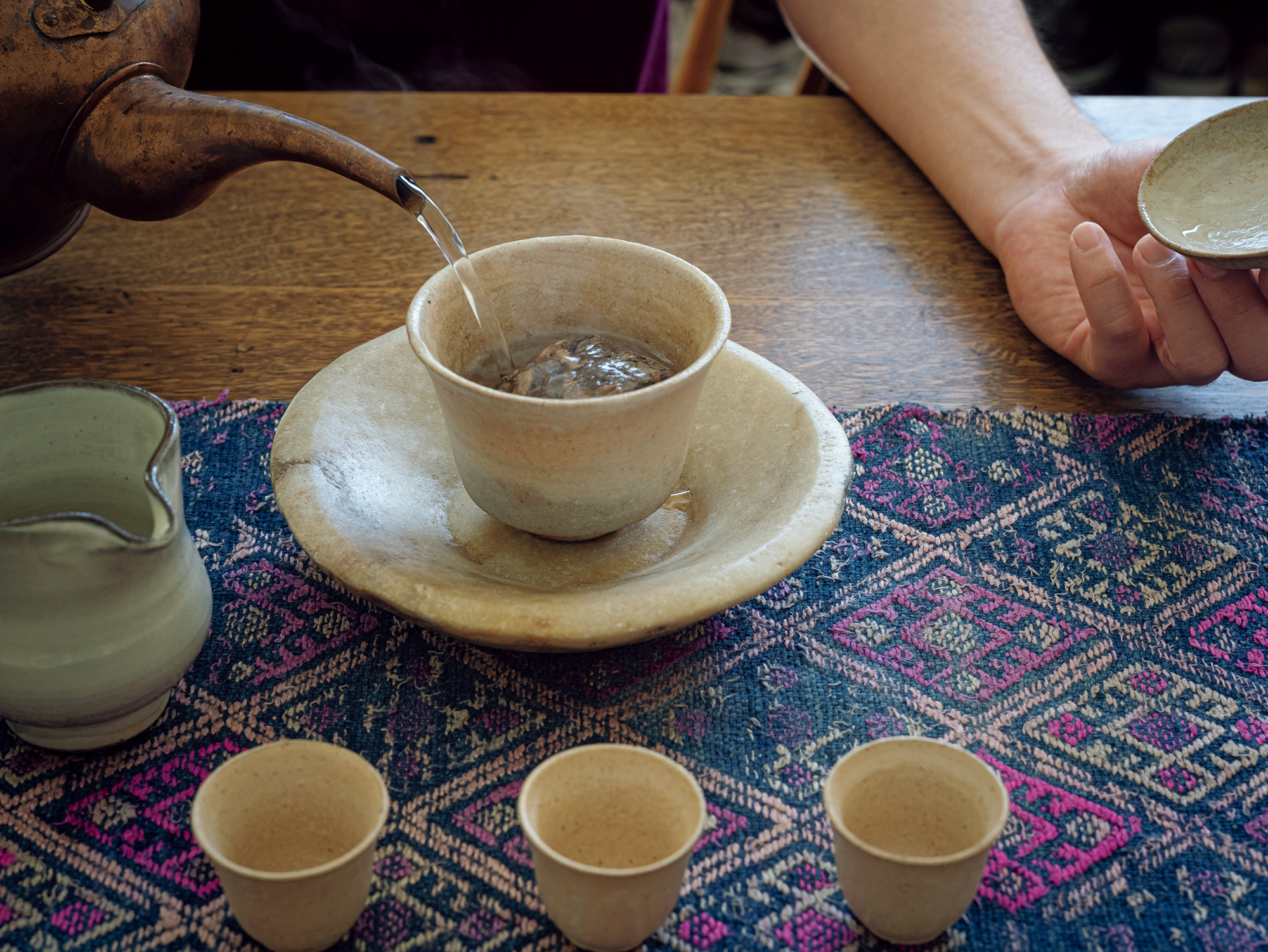 自分の足で探した、味わい深い中国茶。『みんげい おくむら』店主・奥村忍さんのお茶の楽しみ方。茶道具を選ぶ時間も、お茶時間の醍醐味。この日はミャオ族の敷布を敷き、インドで出合った石皿の上に平沢崇義の蓋碗を置いた。 | 茶道具を選ぶ時間も、お茶時間の醍醐味。この日はミャオ族の敷布を敷き、インドで出合った石皿の上に平沢崇義の蓋碗を置いた。