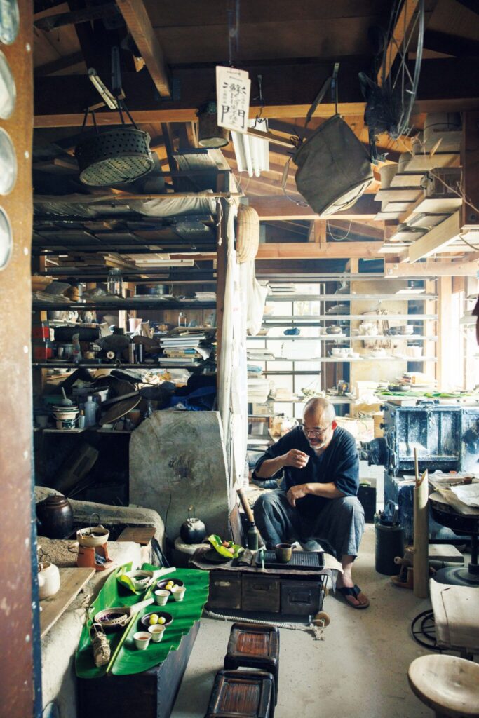 自ら作陶した道具で、"植物"を味わう。陶芸家・茶人、市川 考さんのお茶の楽しみ方。 | 陶工房で茶を振る舞う市川孝さん。市川さんの前にあるのは、缶と木箱を組み合わせた茶車。右側にある筒が、現地の道具を参考に自作したチベットのバター茶用の攪拌器。 自ら作陶した道具で、"植物"を味わう。陶芸家・茶人、市川 考さんのお茶の楽しみ方。