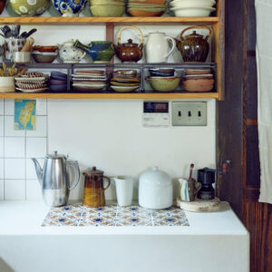 築150年のお勝手を、朗らかな台所に。古民家を改修した、心地よい台所。鳥取〈クラフト館 岩井窯〉の山本教行ら親交の深い窯元、作家の器が棚に並ぶ。モルタルの台には、〈瀬戸本業窯〉を訪ねた際に譲り受けた古い吉祥模様のタイルを埋め込んだ。ステンレスポットの隣は齊藤十郎のポット。「十郎さんからもらったミルをきっかけにハンドドリップが好きになりました」 | 鳥取〈クラフト館 岩井窯〉の山本教行ら親交の深い窯元、作家の器が棚に並ぶ。モルタルの台には、〈瀬戸本業窯〉を訪ねた際に譲り受けた古い吉祥模様のタイルを埋め込んだ。ステンレスポットの隣は齊藤十郎のポット。「十郎さんからもらったミルをきっかけにハンドドリップが好きになりました」　