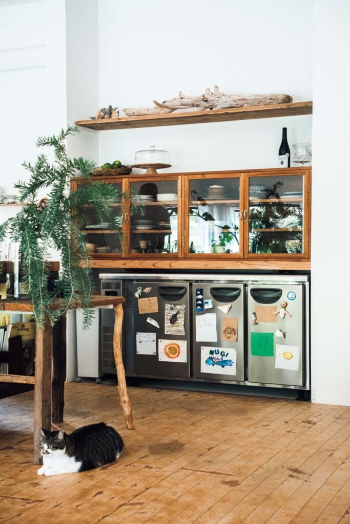 どの角度から眺めても、愛せる場所。自然と家族の真ん中にある、台所。 | もともと窪みのあった空間に合わせて、オーダーメイドの食器棚や業務用冷蔵庫を収めた。息子が描いた絵やメッセージを飾り、大切な時を感じられるように。