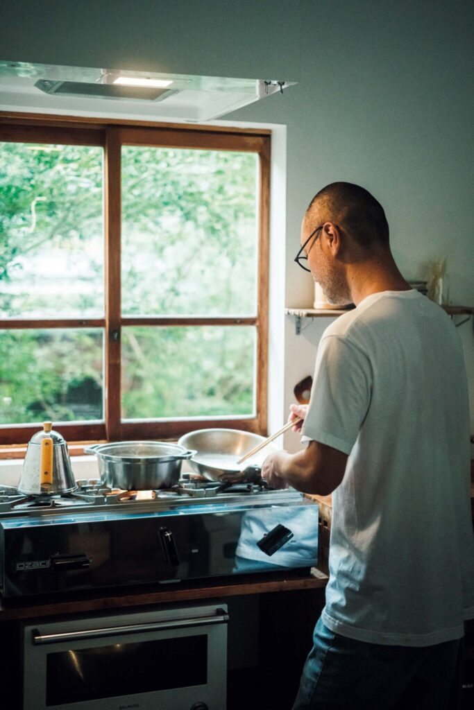 どの角度から眺めても、愛せる場所。自然と家族の真ん中にある、台所。 | 古道具で購入した窓枠の長さを切り出して調整。「目の前には鶏の小屋があります。眺めながら料理をすると和みます」と真悟さん。