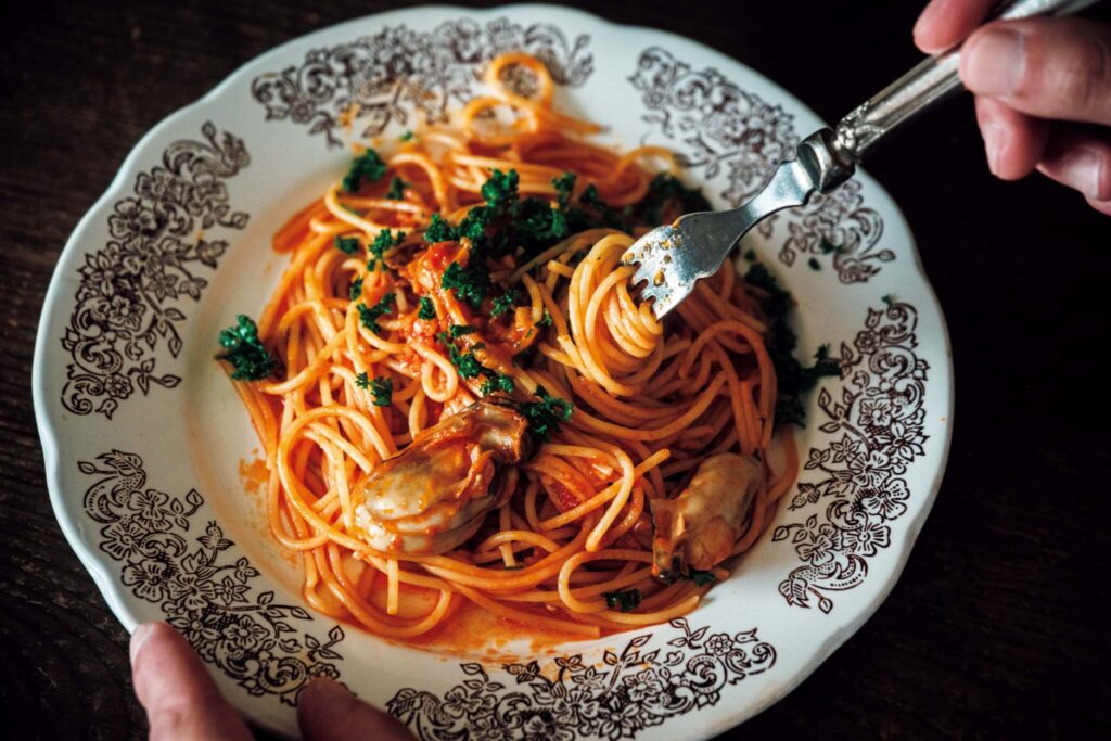 どの角度から眺めても、愛せる場所。自然と家族の真ん中にある、台所。 | 真悟さんがよく作る牡蠣のトマトパスタ。旅先で購入した思い出の器に盛り付けた。「料理を作っている時間は無心になれる。細かな下ごしらえも好きですね」