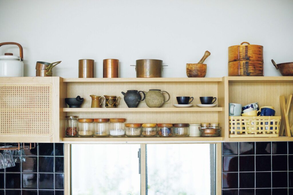 築50年の台所を改修したコックピット。料理家・小堀紀代美さんの台所。 | キッチンの窓の上部に造作した棚には、お茶関係の器やスパイスが。「以前はカラフルなものを並べていましたが、この家ではシックにまとめるほうがしっくりきます」と小堀さん。