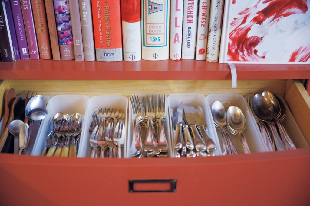 築50年の台所を改修したコックピット。料理家・小堀紀代美さんの台所。 | ダイニングに設置した、本棚の引き出しを開けるとカトラリーが整然と。「分類するのに便利な〈無印良品〉のメイクボックスが、この引き出しに気持ちいいくらいにぴったりだったんです」