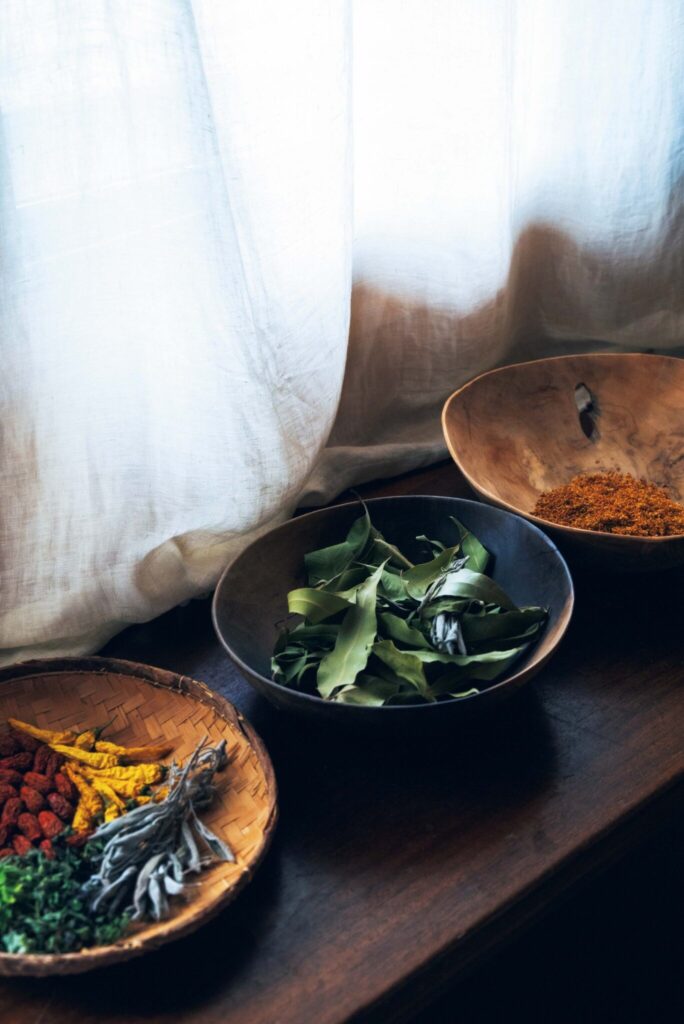 周囲の自然に溶け込む、部材の色に。菓子研究家・長田佳子さんの台所。 | 畑でハーブを育てている長田さん。窓辺の空間にザルやボウルを置き、お茶や料理に活用するハーブや食材をドライに。