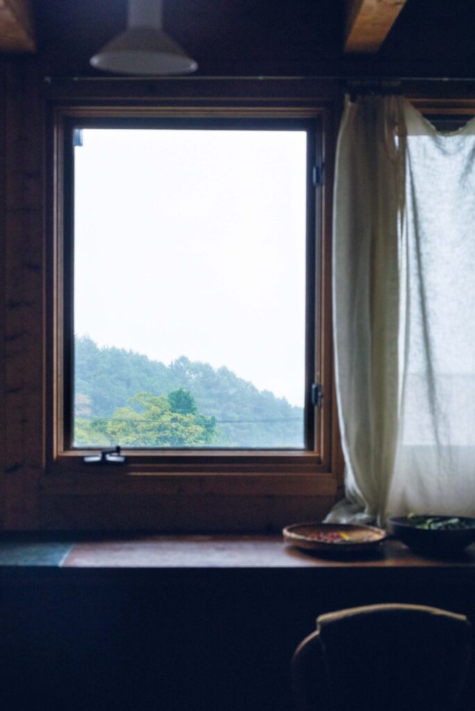 周囲の自然に溶け込む、部材の色に。菓子研究家・長田佳子さんの台所。 | 作業ができるカウンター空間にある縦長の窓。「ここから見える自然や鳥の群れを眺める時間に、心癒やされます」