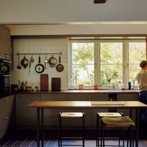 145_p078-085_マーガレット・ハウエル_01 | シンプルで洗練された空間が広がるマーガレット・ハウエルのキッチン。左側の壁に吊るした調理道具は毎日使うもの。手前のダイニングテーブルで食事をすることが多い。