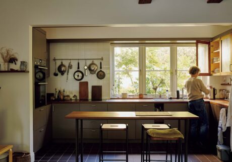 145_p078-085_マーガレット・ハウエル_01 | シンプルで洗練された空間が広がるマーガレット・ハウエルのキッチン。左側の壁に吊るした調理道具は毎日使うもの。手前のダイニングテーブルで食事をすることが多い。 145_p078-085_マーガレット・ハウエル_01 | シンプルで洗練された空間が広がるマーガレット・ハウエルのキッチン。左側の壁に吊るした調理道具は毎日使うもの。手前のダイニングテーブルで食事をすることが多い。