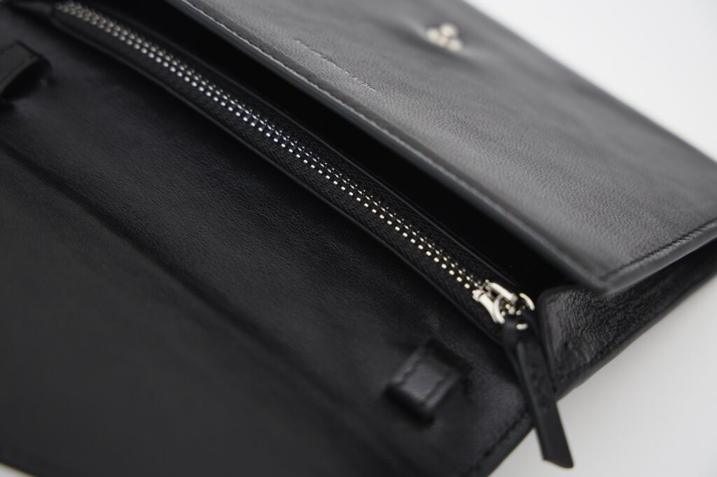 ジップ付きポケットで仕切られた収納スペースのほか、2枚入るカードスロットも。