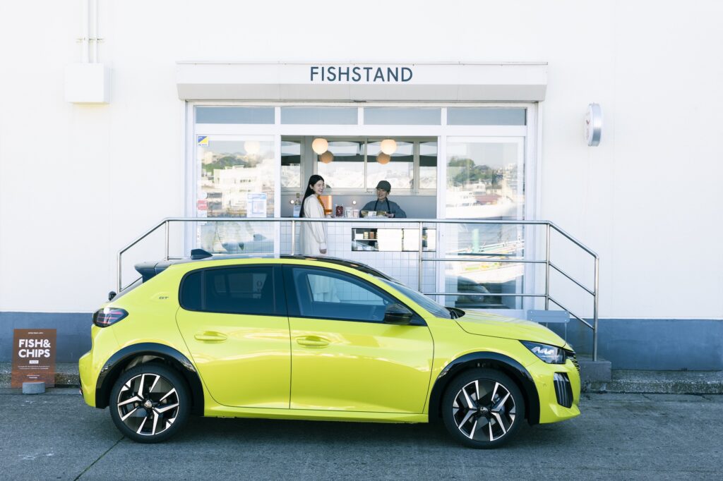 「プジョー 208」で街と海を行き来する。松本有未さんの車のある生活。 | モダンな佇まいの『FISHSTAND』の前で。ボディカラーは新色「アゲダ・イエロー」。ポルトガルの街アゲダの風景から着想を得た、鮮やかな色合い。「光の加減によって、鶯色のような日本人に馴染みのある色みを感じます。特別感と安心感の両方がある色ですね」 「プジョー 208」で街と海を行き来する。松本有未さんの車のある生活。 | モダンな佇まいの『FISHSTAND』の前で。ボディカラーは新色「アゲダ・イエロー」。ポルトガルの街アゲダの風景から着想を得た、鮮やかな色合い。「光の加減によって、鶯色のような日本人に馴染みのある色みを感じます。特別感と安心感の両方がある色ですね」