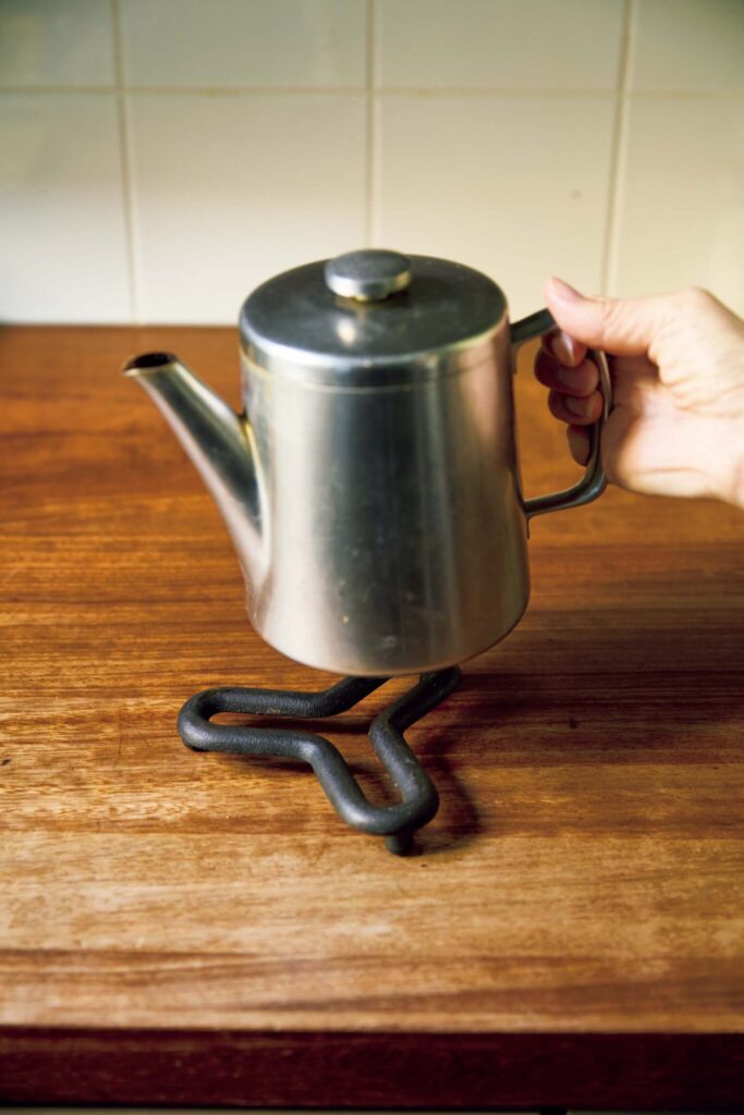 145_p078-085_マーガレット・ハウエル_09 | ステンレス製ポットとポットスタンド
ヴィンテージのオールドホール社のステンレス製ポットはプロダクトデザイナー、ロバート・ウェルチのデザイン。鋳鉄のポットスタンドは、山形県にある〈鋳心ノ工房〉のもの。 145_p078-085_マーガレット・ハウエル_09