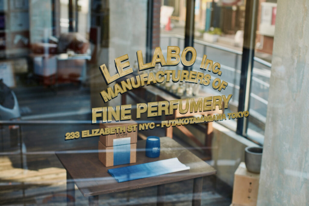 たくさんの光が降り注ぐガラス張りの店内。ゴールドのロゴの先には、藍色がキーとなる限定品のキャンドルが。ルラボ | たくさんの光が降り注ぐガラス張りの店内。ゴールドのロゴの先には、藍色がキーとなる限定品のキャンドルが。