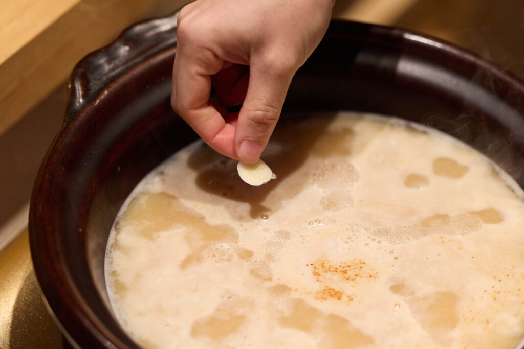 私の大好きな「猪みそ鍋」。写真文：原田アンナベル聖子 (『KOMB』シェフ＆オーナー) #4 | 一味とにんにくのスライスを入れる。
