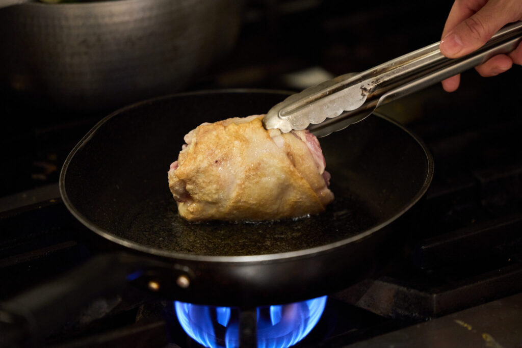 冬にぴったり、体を整える九条ねぎとごぼう鍋のレシピ。写真と文：原田アンナベル聖子 (『KOMB』シェフ＆オーナー) #2 | ③フライパンを熱し、米油を入れ、 鶏もも肉の皮目だけを香ばしく焼く（臭みを抑え、香ばしさを加えるため）。