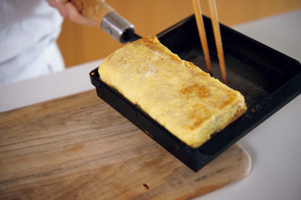 &CookingM_p006-053_献立編_05 | 焼き上がった玉子焼きを縦に回転させてから、まな板に移すと形が崩れにくい。 &CookingM_p006-053_献立編_05 | 焼き上がった玉子焼きを縦に回転させてから、まな板に移すと形が崩れにくい。