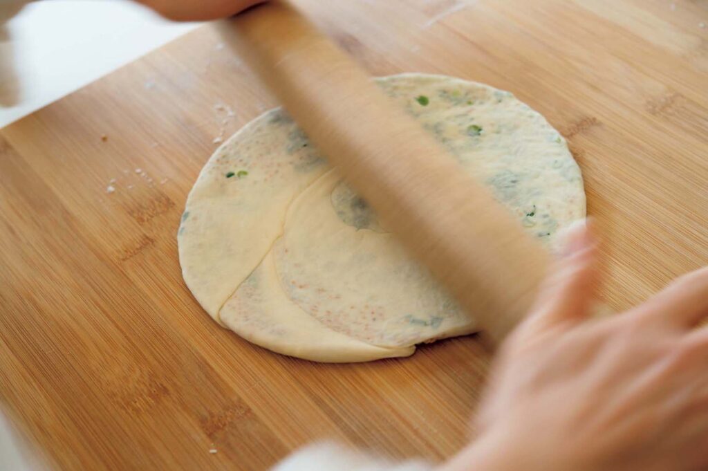 “香のもの”を生かした冬の中華。渡辺有子の料理教室3年目vol.2 | 渦巻き状にした生地を麺棒で押さえて、直径22㎝の円形になるよう薄くのばす。 “香のもの”を生かした冬の中華。渡辺有子の料理教室3年目vol.2 | 渦巻き状にした生地を麺棒で押さえて、直径22㎝の円形になるよう薄くのばす。
