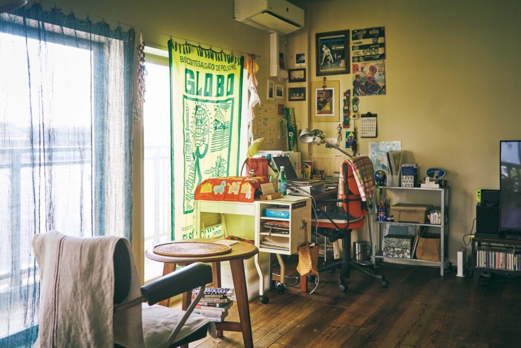 自分史を詰め込むための古くて大きな部屋。卯月えまさんが住む築55年の家。 | カーテンレールに下がるのは、ブラジルのカンガ。インテリアは南米の原色使いに倣う部分が多い。