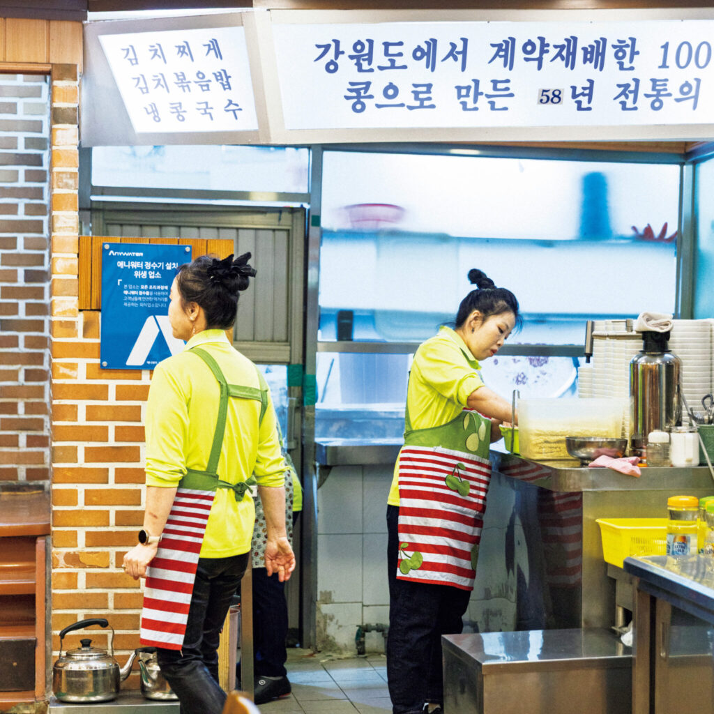 146_p048-055_名店の味_09 | 厨房の上に「カンウォンド契約農家の豆100%、伝統の味」と書かれた看板が。58年とあるが、実際は63
年。 146_p048-055_名店の味_09 | 厨房の上に「カンウォンド契約農家の豆100%、伝統の味」と書かれた看板が。58年とあるが、実際は63
年。