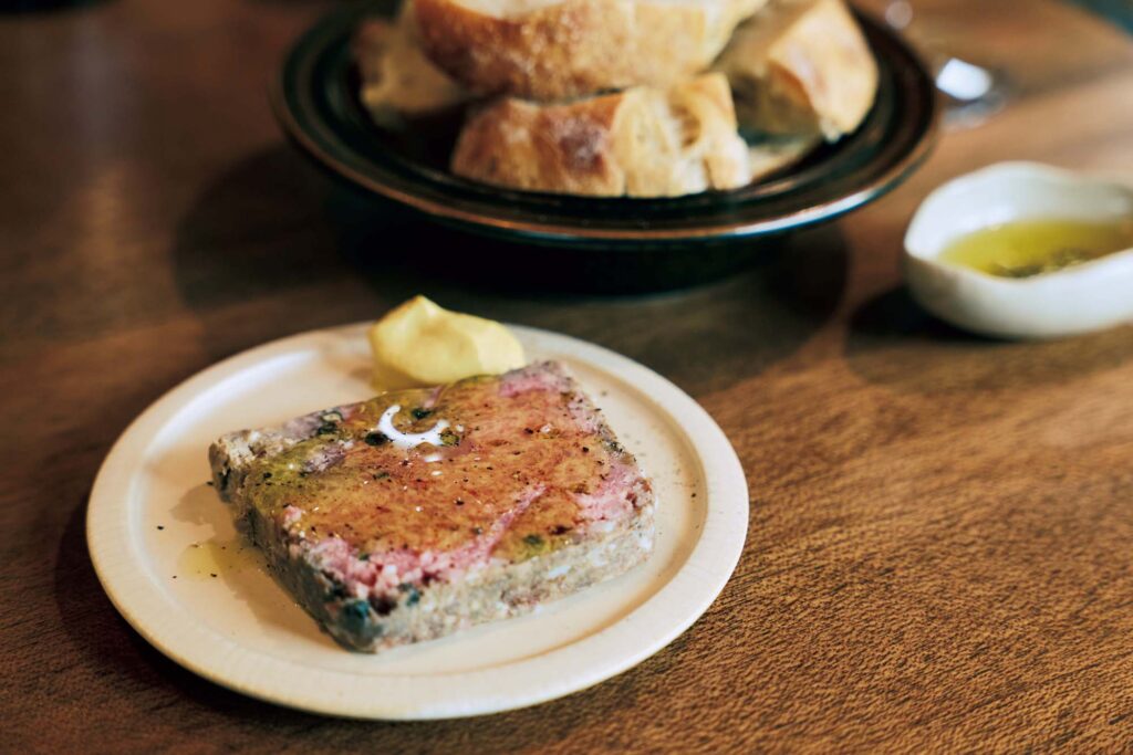 人を引き寄せる、ゆるやかな水辺のリズム。京都・鴨川、ローカルガイド。後編 | 『歩く鳥』と同じビルの1 階には、焼きたてのパンとアテ、ワインを楽しめる『マチ』（左京区聖護院東寺領町8‒1）が。「私はテイクアウトが基本ですが、時折店内利用も。パンをリベイクして、田舎風パテ（ハーフ￥600）と楽しみます」