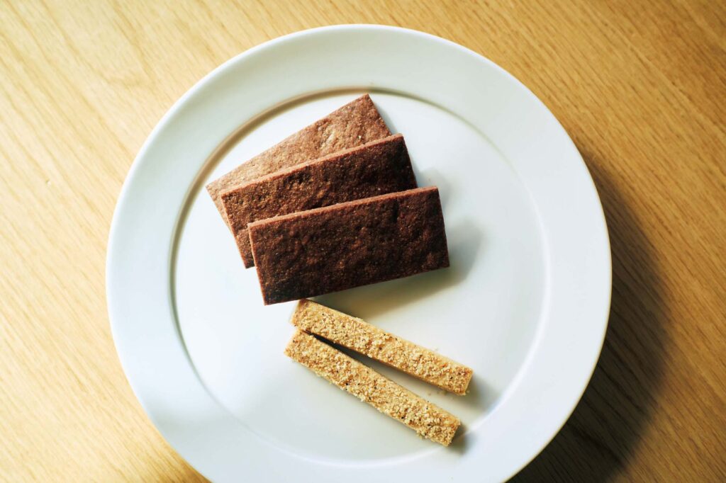 人を引き寄せる、ゆるやかな水辺のリズム。京都・鴨川、ローカルガイド。後編 | セレクト食材店『マニーナ』（左京区難波町211‒5）では、オリジナルの焼き菓子がラインナップ豊富に。有機材料をベースにした卵不使用のアマゾンカカオビスケット（ 1 箱￥1,3
00）、ビールが進む味わいのチーズスティック（ 1 箱￥1,000）。