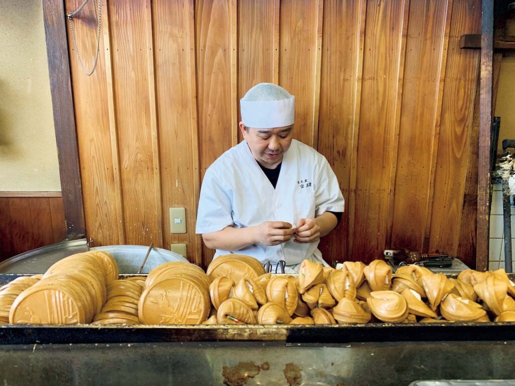 名所の顔の向こう側にあるいいところ。伏見稲荷に行くなら、立ち寄りたい2軒。3代目の松久武史さんが家族と営む。昭和初期に岐阜の味噌煎餅を京の白味噌を使って焼いたのが始まり。鈴せんべい1個￥120。