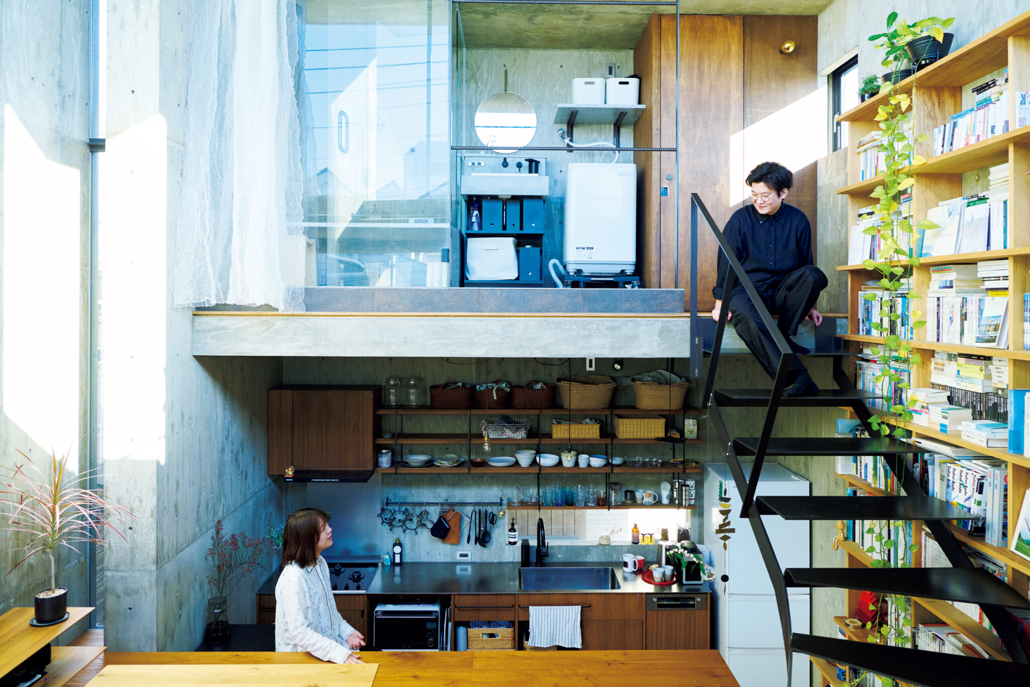 躯体の中の4層構造に暮らす。五十嵐理人さんが腰掛けているのは家の最上部の洗面所&バスルームと中2階をつなぐ鉄骨階段。妻の友子さんは、さらに半階分レベルを下げたキッチンに立っている。 | 五十嵐理人さんが腰掛けているのは家の最上部の洗面所&バスルームと中2階をつなぐ鉄骨階段。妻の友子さんは、さらに半階分レベルを下げたキッチンに立っている。 躯体の中の4層構造に暮らす。五十嵐理人さんが腰掛けているのは家の最上部の洗面所&バスルームと中2階をつなぐ鉄骨階段。妻の友子さんは、さらに半階分レベルを下げたキッチンに立っている。 | 五十嵐理人さんが腰掛けているのは家の最上部の洗面所&バスルームと中2階をつなぐ鉄骨階段。妻の友子さんは、さらに半階分レベルを下げたキッチンに立っている。